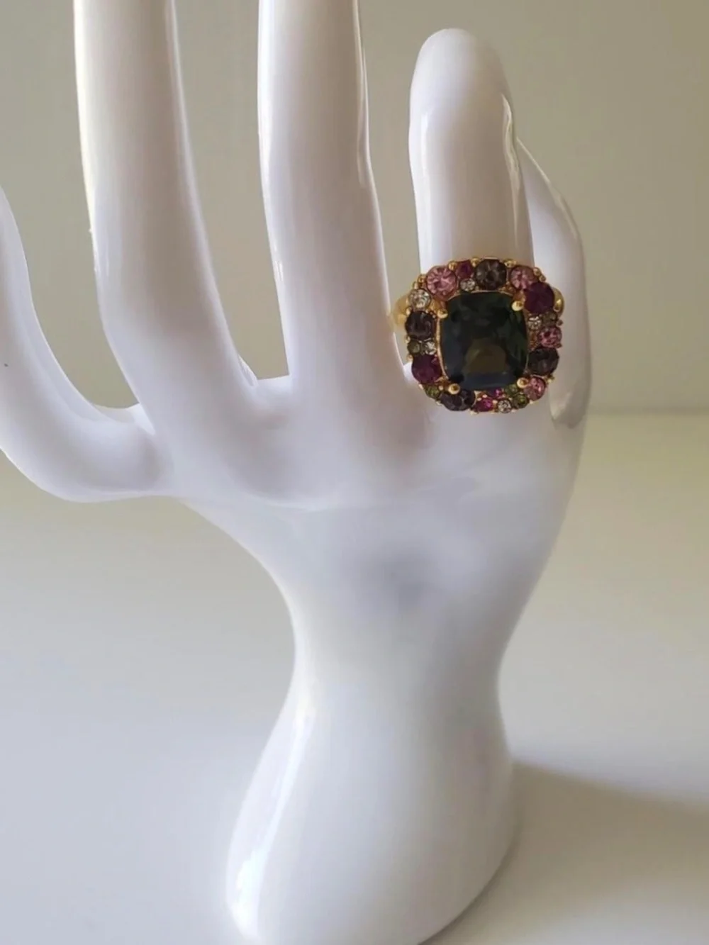 Gold ring with green central gemstone surrounded by pink and red rhinestones